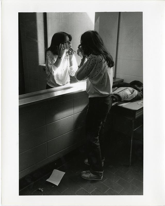 Student applying makeup in mirror