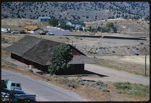 Elevated view of buildings at base of hill spotted with trees, likely Nevada