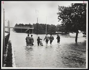 On Storrow Drive-At least six people enjoyed themselves during the floods that hit Boston and the rest of the state. They are walking along the drive, which is under a foot of water. The Charles River overflowed its banks, inundating the Esplanade.