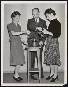 Seattle Inventor Perfects New Food Grinding Machine for Making Liquid Diet. Mr. Frank H. Chester, Seattle inventor, is shown above demonstrating to Miss Ruth Chitty, (left) and Miss Josephine Ryan, (right) his new machine for making liquid nourishment out of all kinds of food. The invention, called a "Vitamizer", will pulverize any sort of food placed in the glass container, by the tiny blades that whirl at 20,000 revolutions per minute. By adding a little water of milk, one can drink even a steak, as a liquid diet. Physicians hail the invention as valuable, because with it, one can reduce foods in such a manner that all their nutritive content can be absorbed by digestion. Mr. Chester expects to start manufacturing the machines at a plant here in Seattle.