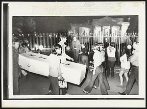 Sidewalk Display-- Youths carry a mock coffin with the work "Kill" inscribed on the lid past the White House last night as President Nixon was meeting with reporters in the East Room.