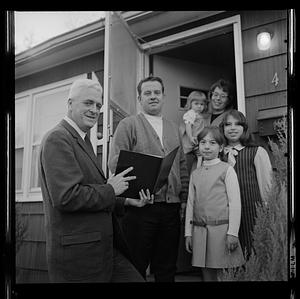 Norman Doyle showing a document to a family in their doorway