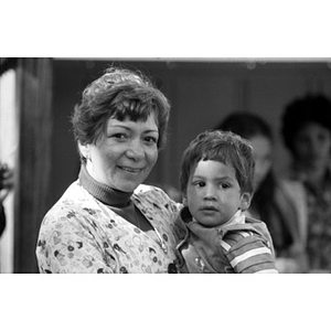 Head-and-shoulders portrait of a woman holding a little boy in her arms at a Latino festival
