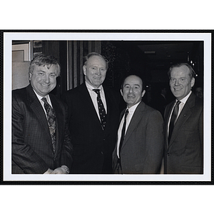 Four men stand together and smile for the camera at a St. Patrick's Day Luncheon