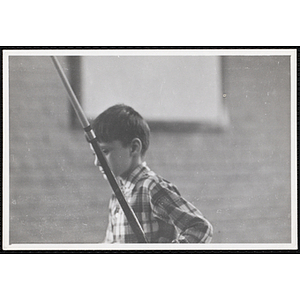A boy from the Boys' Clubs of Boston holding a cue