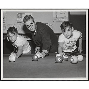 Two boys and an adult pose for a shot at a billiards table
