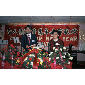 Suzanne Lee stands with a man who addresses a crowd from a microphone during the Chinese Progressive Association's celebration of the Lunar New Year