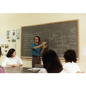 Three students in a job placement class sit listening to their teacher at the front of the room