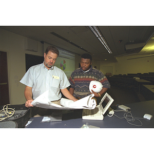 Workers install computer equipment in a classroom in Shillman Hall