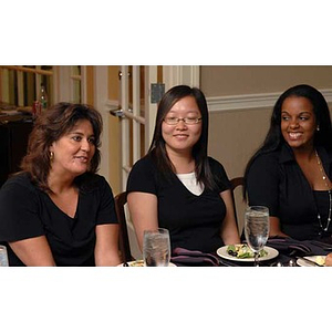 A woman sits with two Torch Scholars at the Manganaro Luncheon