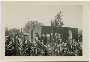 Four men and a woman in front of an abode building