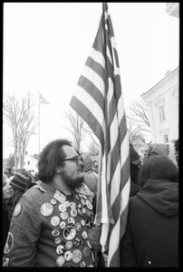 Protester with an American flag, decked out in antiwar buttons, during a demonstration against the invasion of Laos