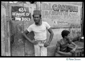 Jimmy Cliff standing by a sign 'Beware of tigers and bad dogs' near his old home on Spanish Town Road