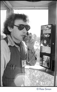 Charles Light (wearing a press pass for Green Mountain Post Films) using a pay phone