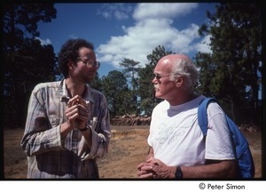 Ram Dass (right) speaking to a man in a forest clearing