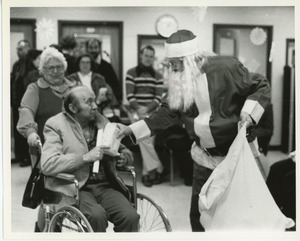 Santa Claus handing gifts to client at Christmas party