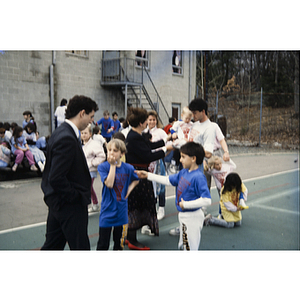 Man speaking to two boys in a crowd outside Eastern Middlesex Family YMCA