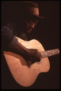 Mississippi John Hurt: studio portrait, seated, playing guitar