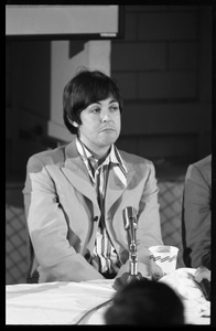 Paul McCartney seated in front of a microphone at a table, during a Beatles press conference