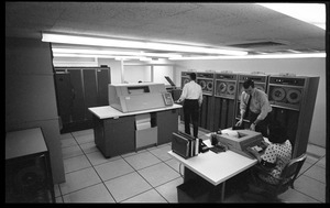 Computer room scene: woman entering data into a console, with Honeywell Model 400 mainframe and printer in background