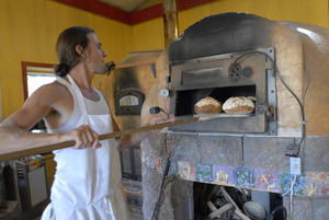 Hungry Ghost Bread: owner and baker Jonathan C. Stevens removing loaves of bread from the oven