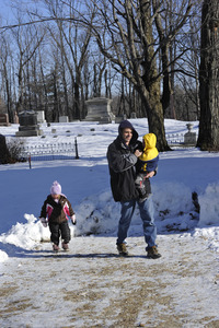 Parent and young children walking through snow in front of the Center Cemetery in New Salem center