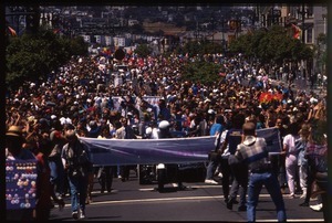 Massive crowd marching in the San Francisco Pride Parade, carrying banner reading 'Mayors contingent': Art Agnos waving to the crowd from the back of an automobile