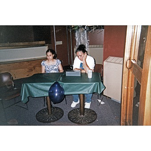 Woman and teenage girl sitting at a table with a cash box in the lobby of the Jorge Hernandez Cultural Center.