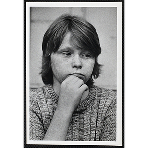 A boy from the Boys' Clubs of Boston looking off to his left with his hand on chin