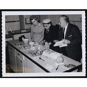 Two women and and a man evaluate finshed dishes in a kitchen