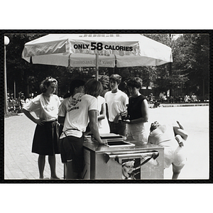 A >teenage boy operating an ice juice cart speaks with people on Boston Common