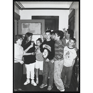 Children gather by a door with site coordinators Josh Kraft and Liz Cinquino at the Tri-Club slide show at the Charlestown Clubhouse