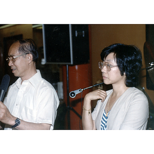 Henry Wong speaks from a microphone with Suzanne Lee beside him at a welcome dinner held for Chinese Ambassador Zhang Wenjin in Boston
