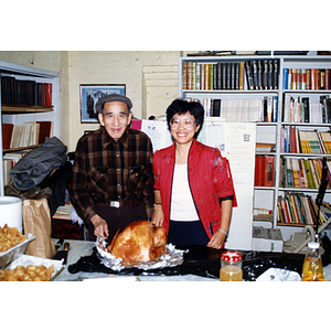 Suzanne Lee stands with a man at a Thanksgiving celebration held by the Chinese Progressive Association, with a turkey in front of them