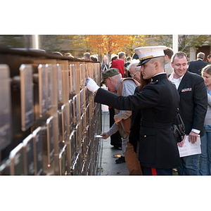 A man in a military uniform touches a plaque on the Veterans Memorial at the dedication ceremony