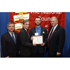 An unidentified inductee poses with his certificate and three men at the National Council Dinner