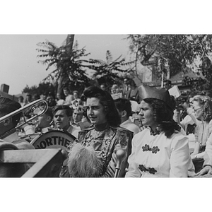 Two female band members sit in the stands of a football game