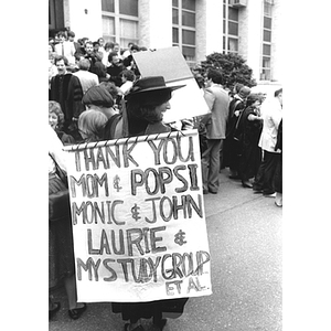 A Law School graduate with a sign holds up her degree