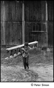 Laura Bradley carrying a ladder past the barn, Montague Farm commune