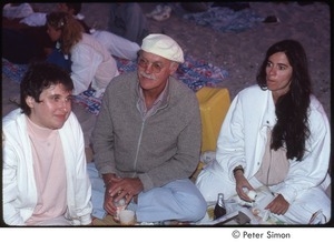 Ram Dass sitting on the beach with two unidentified women