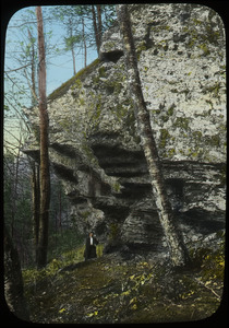 Hiker beneath rock cliff in woods