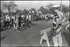 Antiwar demonstration at Fort Dix, N.J.: line of protesters marching past barbed wire and military police barricade