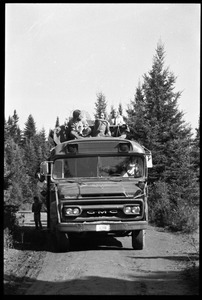 GMC bus driving down a dirt road with passengers on top, Earth People's Park