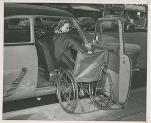 Woman climbing out of a car into a wheelchair