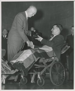 President Dwight D. Eisenhower handing a plaque to an unidentified man in a wheelchair