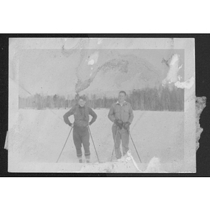 Two people posing outside in snow on skis