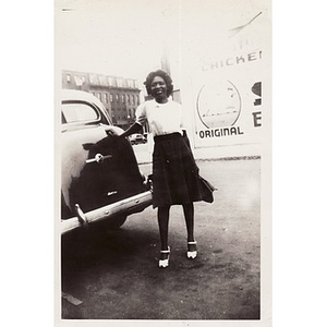 An unidentified woman leans against the back of a car