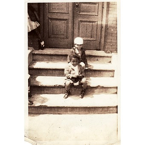 Two unidentified children sit on a set of stairs