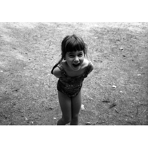 Little girl in a bathing suit laughing.