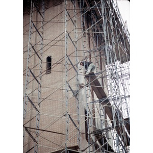 Construction worker on the scaffolding that surrounds the tower of a former church.